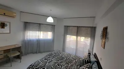 a bedroom with a bed and a desk and windows at City center beach and supermarket walking distance in Limassol