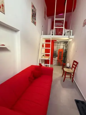a red couch in a room with a loft bed at RED Cabin-Larnaca Centrum in Larnaka