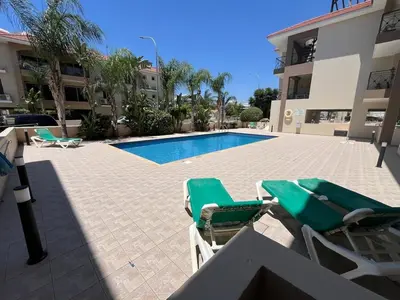 two lawn chairs and a swimming pool in front of a building at 2 Bedroom Penthouse Apartment With Swimming Pool in Kiti