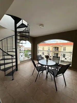 a dining room with a table and chairs and a spiral staircase at 2 Bedroom Penthouse Apartment With Swimming Pool in Kiti