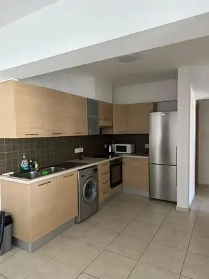 a kitchen with wooden cabinets and a stainless steel refrigerator at 2 Bedroom Penthouse Apartment With Swimming Pool in Kiti