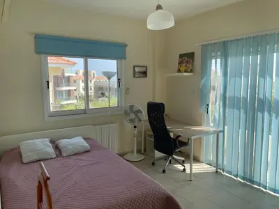 a bedroom with a bed and a desk and a window at Holiday House in Oroklini in Voroklini