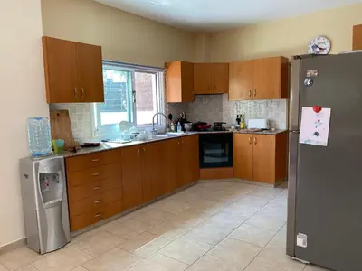 a kitchen with wooden cabinets and a stainless steel refrigerator at Holiday House in Oroklini in Voroklini