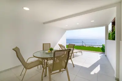 a dining room with a table and chairs and the ocean at Wavestone Beachfront House in Meneou