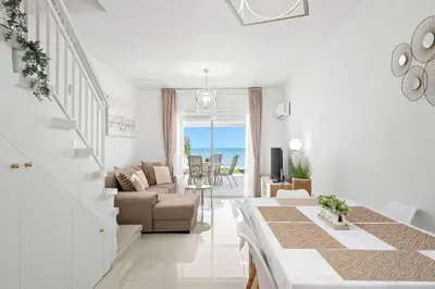 a white living room with a table and a couch at Wavestone Beachfront House in Meneou