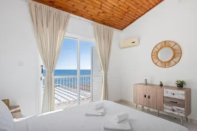 a bedroom with a large window with a view of the ocean at Wavestone Beachfront House in Meneou