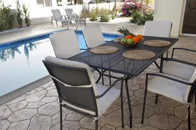 a table with chairs and a bowl of fruit next to a pool at Villa Elise in Protaras