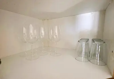 four empty wine glasses sitting on a shelf at Sunny 2BR Getaway Steps from the Beach with Wi-Fi in Larnaka