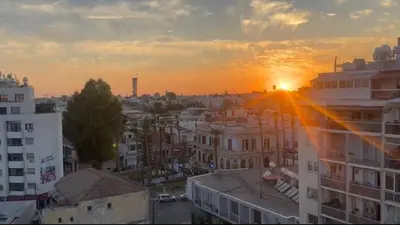 a view of a city with the sun setting behind buildings at New Central 2 bedroom Apartment in Limassol