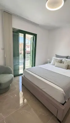 a white bedroom with a bed and a chair at Luxury Beach Villa 2 min Walk to Sea & Airport in Meneou