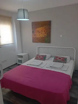 a bedroom with a white bed with a pink blanket at Smart 2 Bedroom Flat in Larnaka