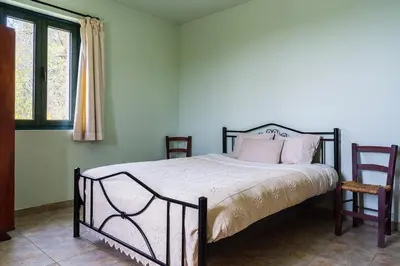 a bedroom with a bed with pink pillows and two chairs at Mountain Retreat in Kyperounda