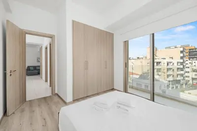a white bedroom with a bed and a large window at Downtown City View 2 Bedroom Apartment in Larnaka