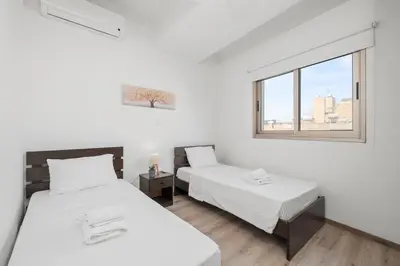 two beds in a room with a window at Downtown City View 2 Bedroom Apartment in Larnaka