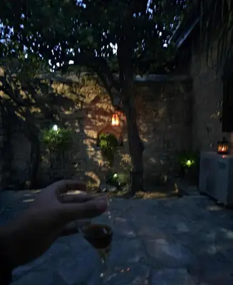 a person holding a glass of wine in the dark at Οίκος Λόφου-oikos Lofou in Lofou