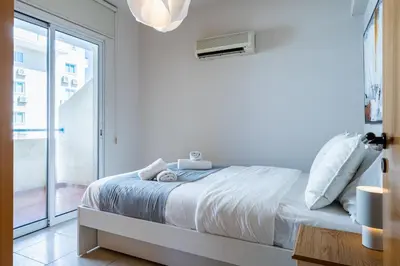 a white bedroom with a bed and a window at Calina - 3BR Apt W Pool & Balcony in Mackenzie in Larnaka