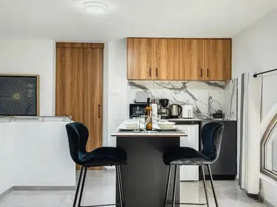 a kitchen with black chairs at a counter with a refrigerator at Super Views Larnaca in Larnaka
