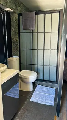a bathroom with a toilet and a shower with blue mats at Centrally located studio with Mountain & Sea views in Avdhelleron