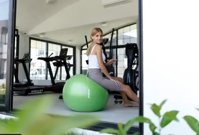 a woman sitting on an exercise ball in a gym at Kıbrıs Girnede 1 yatak odalı Süper lüks havuzlu daire in Vuda
