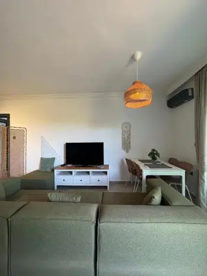 a living room with a couch and a tv at Kıbrıs Girnede 1 yatak odalı Süper lüks havuzlu daire in Vuda