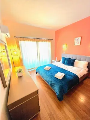 a bedroom with a large bed with a blue blanket at Finikoudes Fabulous Apartment in Larnaka