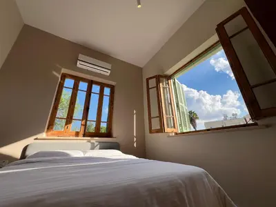 a bedroom with a bed and a large window at 1947 Rescued Stone House in Nicosia