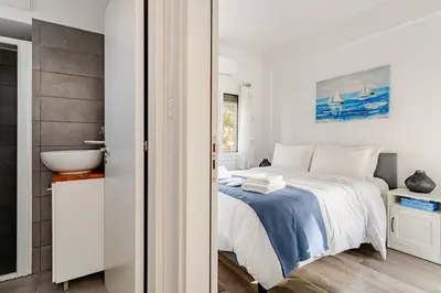 a white bedroom with a bed and a sink at Cozy beachfront gem with seaview in Limassol