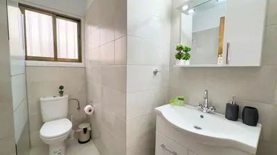 a white bathroom with a toilet and a sink at SundyBeach Beachfront 2Bdr Dhekelia in Larnaka