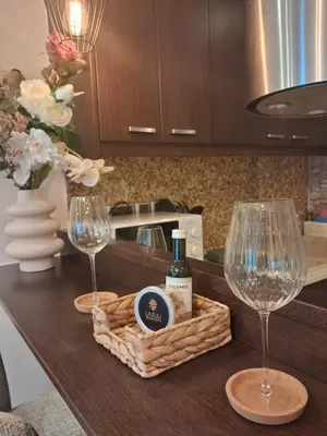 two wine glasses and a basket on a table with wine bottles at Lazuli Sea View Beachfront Studio Nr 305 in Larnaka