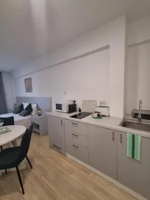 a kitchen with white cabinets and a table and a couch at Lazuli City Center Studio 161 - 100 m from the beach in Larnaka