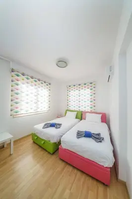 two beds in a room with white walls and wood floors at Villa Waves in Mazotos