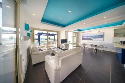 a living room with white furniture and a blue ceiling at Villa Waves in Mazotos