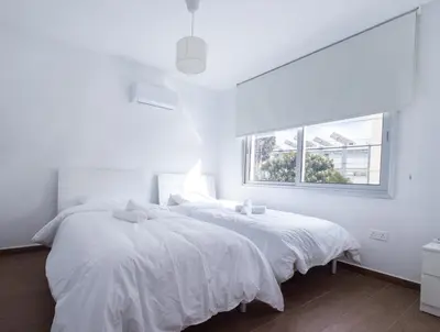 two beds in a white bedroom with a window at Maestro Family - Apartment in Larnaka