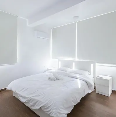 a white bedroom with a white bed with two towels on it at Maestro Family - Apartment in Larnaka
