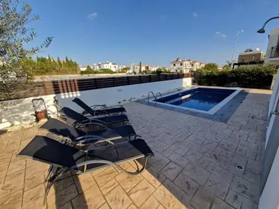 a group of lounge chairs next to a swimming pool at Sunshine Villa Kapparis in Paralimni