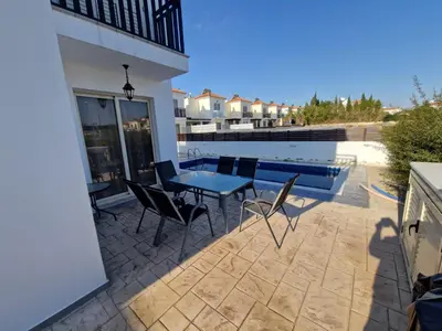 a patio with a table and chairs next to a swimming pool at Sunshine Villa Kapparis in Paralimni