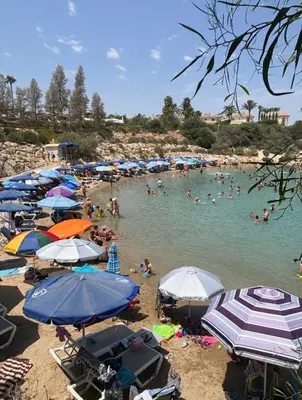 a beach with many umbrellas and people in the water at Kapparis Beach Escape in Paralimni