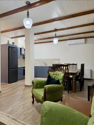 a living room with green chairs and a table at To Petrino 2 Apartment -Authentic Comfort in the Heart of Kalopanayiotis in Kalopanayiotis