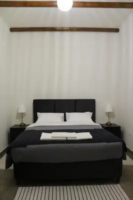 a bedroom with a large black bed with two lamps at To Petrino 2 Apartment -Authentic Comfort in the Heart of Kalopanayiotis in Kalopanayiotis
