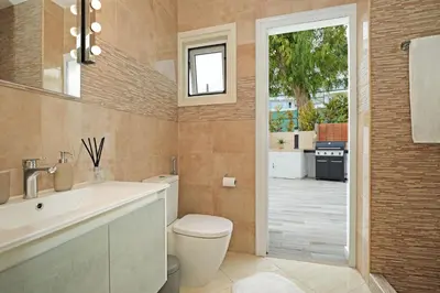 a bathroom with a toilet and a sink and a window at Villa Amy - 100m from Nisia Loumbardi Beach in Protaras