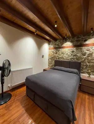 a bedroom with a bed and a stone wall at To Petrino 4 Studio- Nature, Comfort & Tradition Under One Roof in Kalopanayiotis