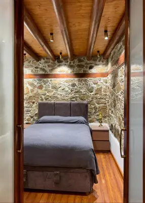 a bed in a room with a stone wall at To Petrino 4 Studio- Nature, Comfort & Tradition Under One Roof in Kalopanayiotis