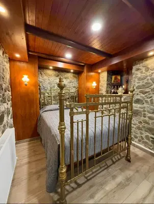 a bedroom with a bed and a stone wall at To Petrino 5 -Apartment- Nature, Comfort & Tradition Under One Roof in Kalopanayiotis