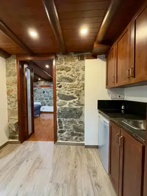 a kitchen with wooden cabinets and a stone wall at To Petrino 5 -Apartment- Nature, Comfort & Tradition Under One Roof in Kalopanayiotis