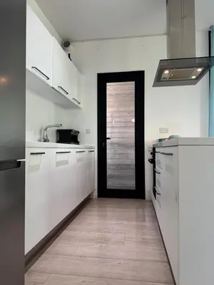 a kitchen with white cabinets and a black door at The Qube Residence 2 Bedroom Premium Apartment in Limassol