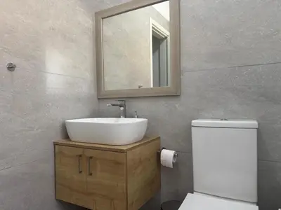a bathroom with a sink and a mirror and a toilet at The Qube Residence 2 Bedroom Premium Apartment in Limassol