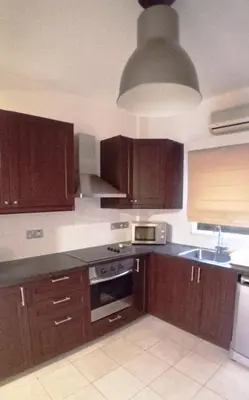 a kitchen with wooden cabinets and aendant light at Ayia Napa Marina Luxury Villas - Sapphire in Ayia Napa