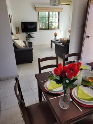 a dining room with a table with red flowers on it at Ayia Napa Marina Luxury Villas - Sapphire in Ayia Napa