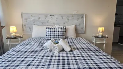 a bed with a blue and white plaid blanket and two night stands at STAY Armonia Central Suite in Nicosia