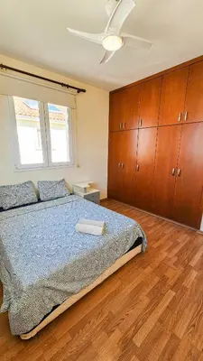 a bedroom with a bed with a ceiling fan and wooden cabinets at Townbeach Villa with Private Pool in Voroklini